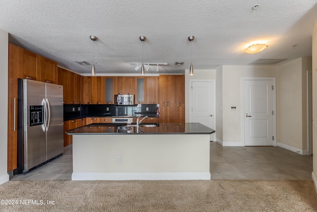 kitchen featuring hanging light fixtures, light tile patterned floors, a kitchen island with sink, appliances with stainless steel finishes, and sink