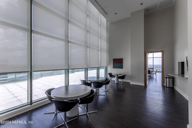 dining room featuring a towering ceiling, dark wood-type flooring, and a wealth of natural light