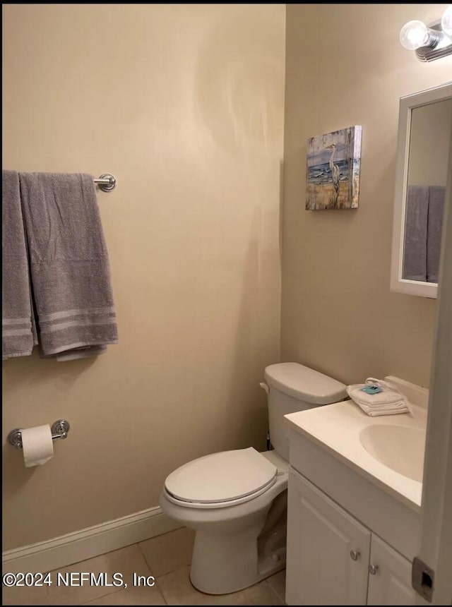 bathroom with toilet, vanity, and tile patterned floors