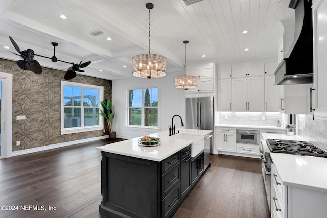 kitchen with white cabinets, decorative light fixtures, a kitchen island with sink, dark hardwood / wood-style floors, and ceiling fan with notable chandelier