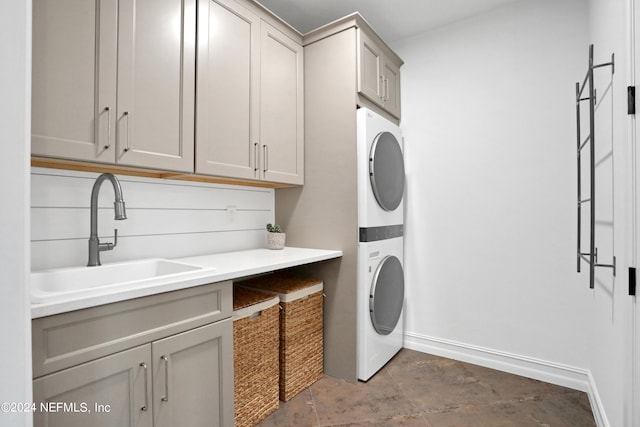 clothes washing area with cabinets, sink, and stacked washing maching and dryer