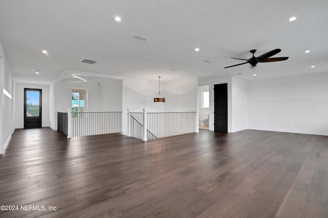 unfurnished living room featuring ceiling fan and dark wood-type flooring