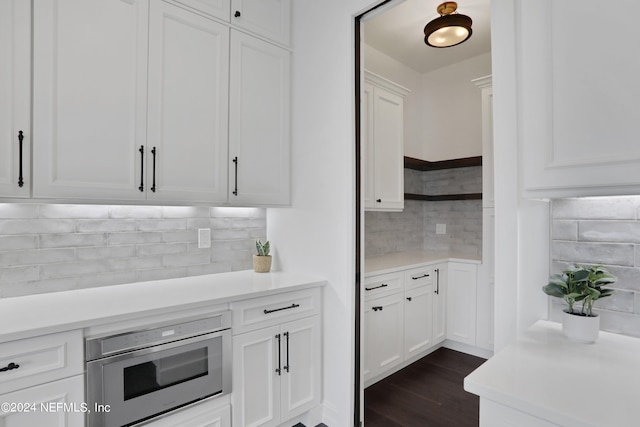 kitchen with white cabinets, dark wood-type flooring, and tasteful backsplash