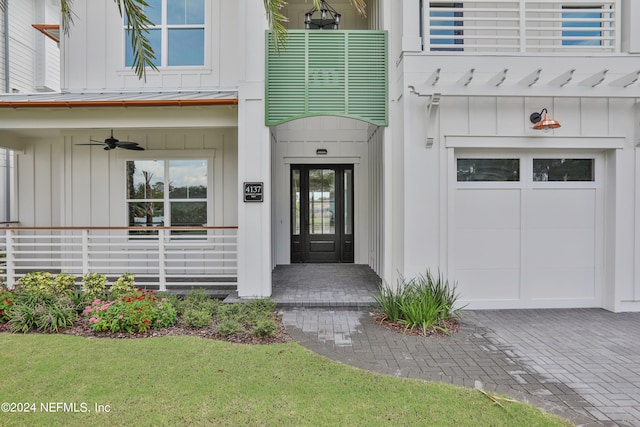 property entrance with ceiling fan, a garage, and a lawn