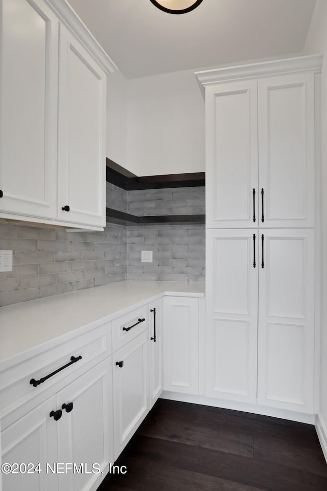 kitchen with backsplash, dark hardwood / wood-style flooring, and white cabinetry