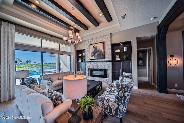 living room with a textured ceiling, a stone fireplace, an inviting chandelier, built in features, and hardwood / wood-style flooring