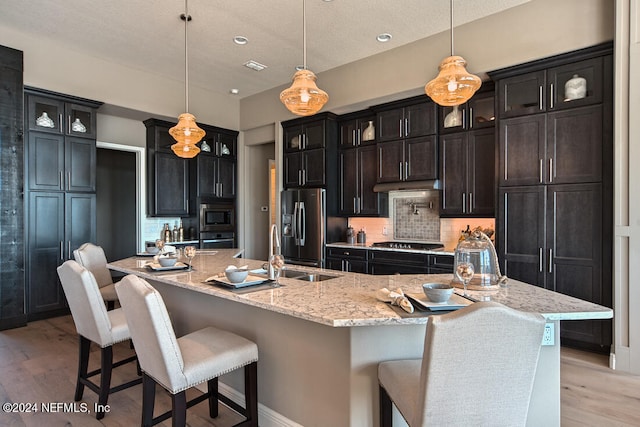 kitchen featuring appliances with stainless steel finishes, sink, a large island with sink, and decorative light fixtures