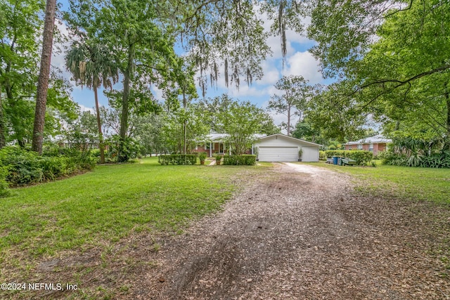 view of front of property featuring a front yard, an attached garage, and dirt driveway