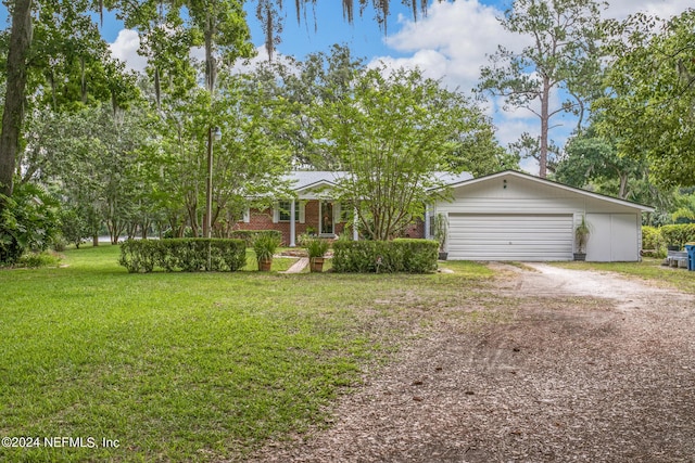 view of front of house featuring an attached garage, dirt driveway, a front yard, and brick siding