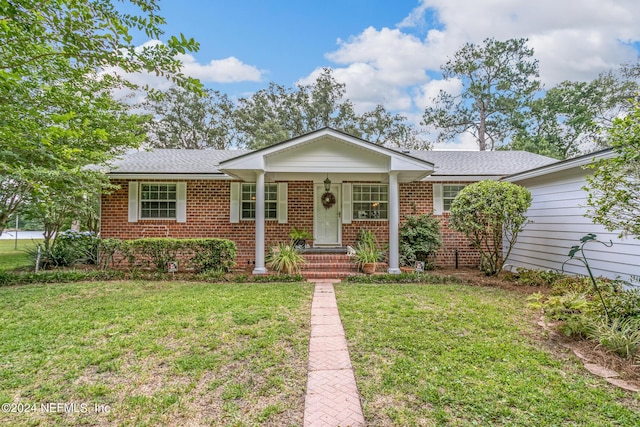 single story home featuring a front lawn, roof with shingles, and brick siding