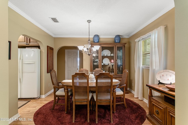 dining area with an inviting chandelier, baseboards, arched walkways, and crown molding