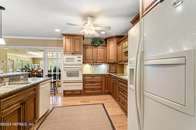 kitchen with a warming drawer, brown cabinetry, light stone countertops, light wood-type flooring, and white appliances