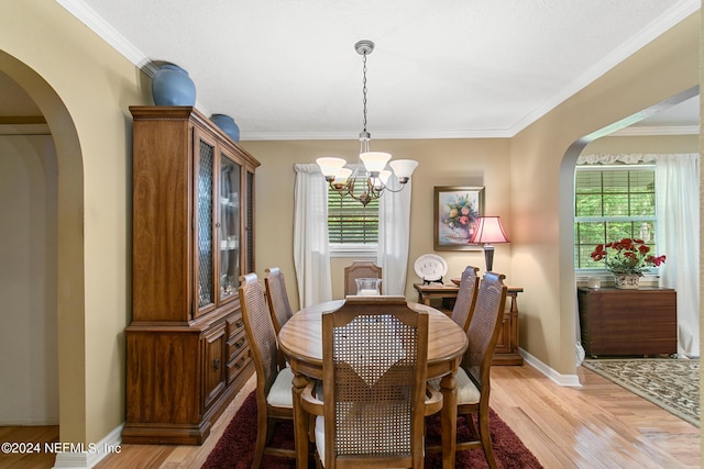 dining space with arched walkways, light wood finished floors, crown molding, and an inviting chandelier