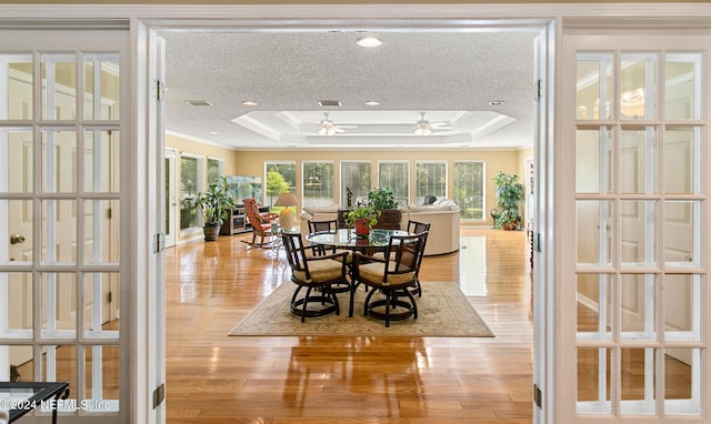 sunroom / solarium featuring a tray ceiling, french doors, visible vents, and ceiling fan