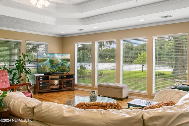 living area with a textured ceiling, ornamental molding, and wood finished floors