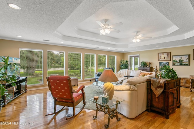 living room with a tray ceiling and light wood-style flooring