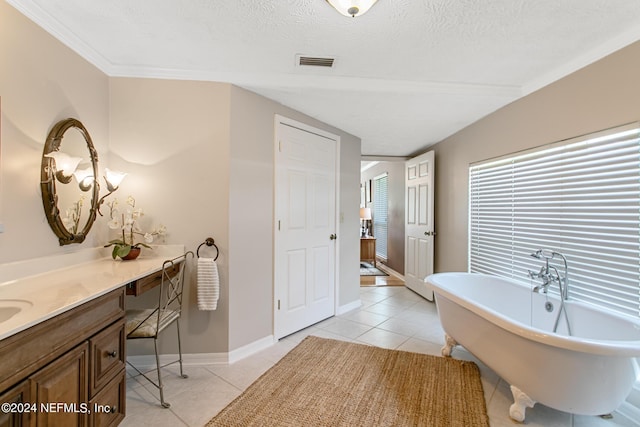 full bath with visible vents, a freestanding bath, vanity, and tile patterned floors