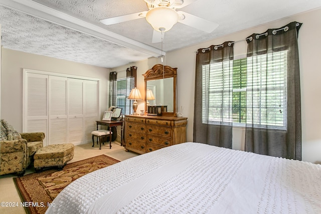 bedroom featuring carpet floors, a closet, multiple windows, and a textured ceiling