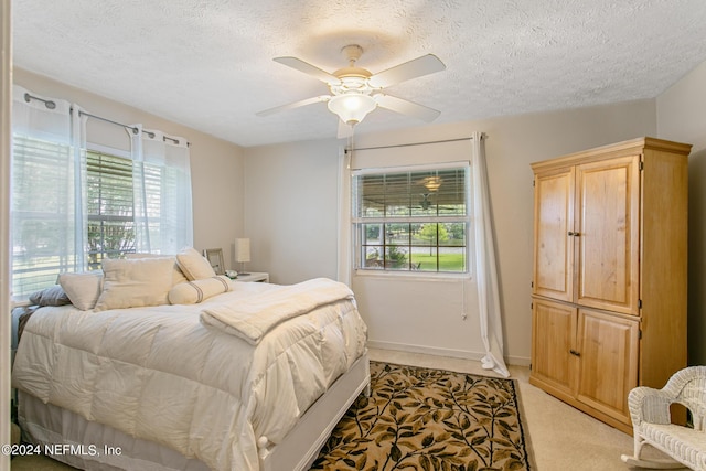 bedroom featuring light carpet, multiple windows, a textured ceiling, and baseboards