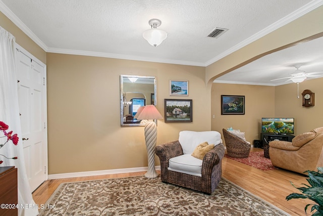 sitting room featuring ornamental molding, arched walkways, visible vents, and wood finished floors