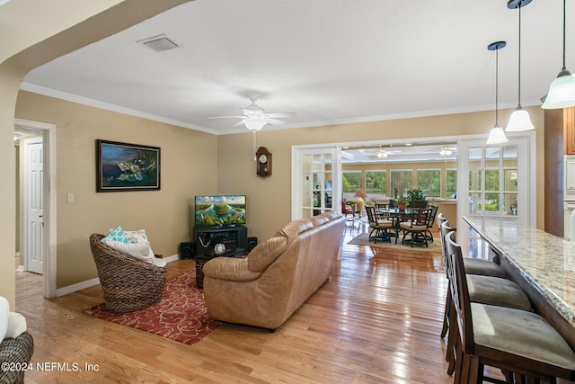 living area featuring baseboards, ornamental molding, visible vents, and light wood-style floors