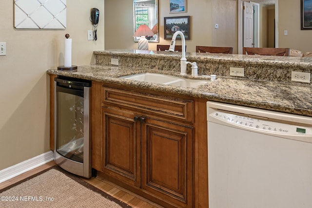 bar with white dishwasher, beverage cooler, wood finished floors, a sink, and baseboards