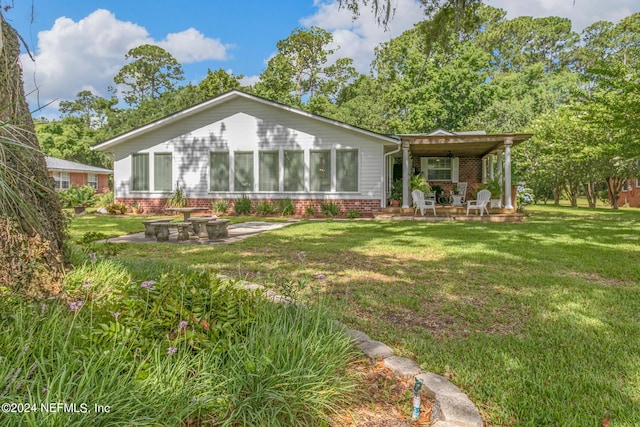 back of property featuring a patio, a lawn, and brick siding