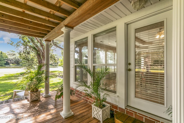 exterior space with a water view, ornate columns, beam ceiling, and a wealth of natural light