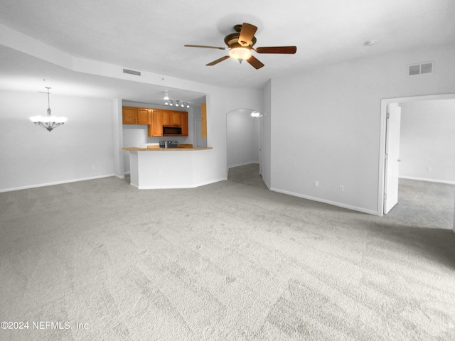 unfurnished living room featuring ceiling fan with notable chandelier and carpet flooring