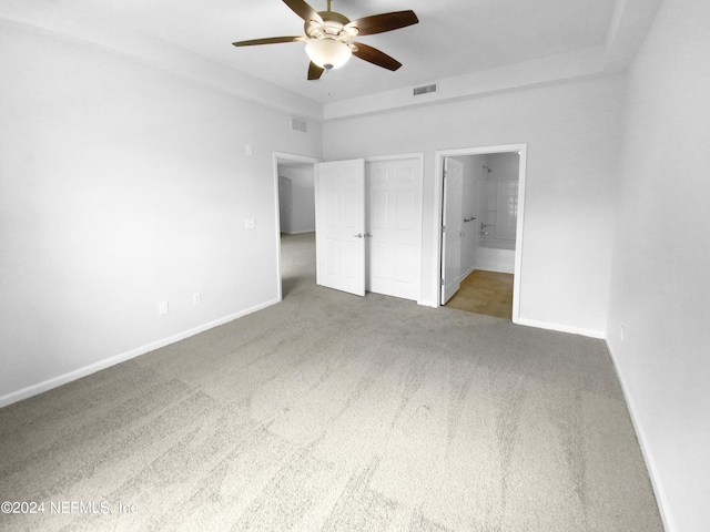 unfurnished bedroom with ensuite bath, ceiling fan, and dark carpet