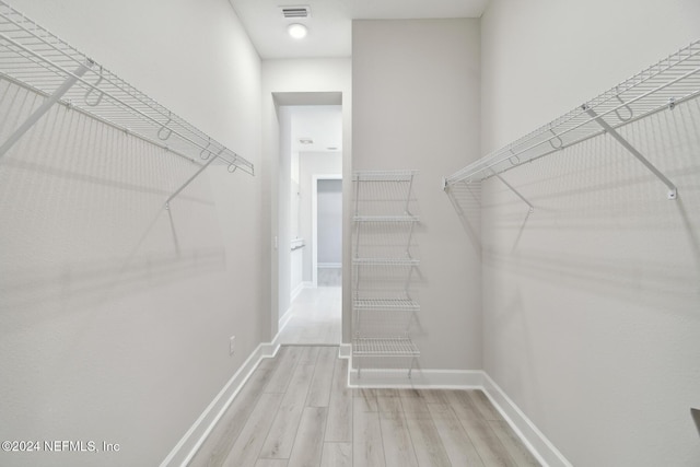 walk in closet with light hardwood / wood-style flooring