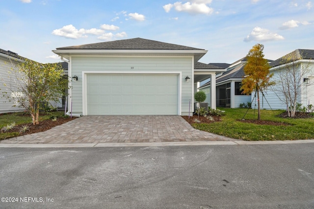 view of front facade with central AC, a garage, and a front lawn