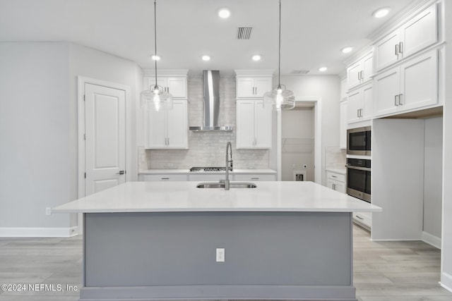 kitchen with a center island with sink, wall chimney exhaust hood, and decorative light fixtures