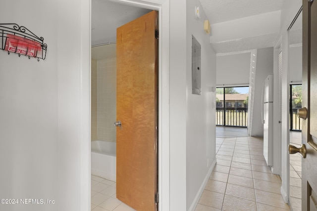 hallway featuring a textured ceiling, light tile patterned flooring, and electric panel