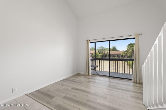 empty room with high vaulted ceiling and light wood-type flooring