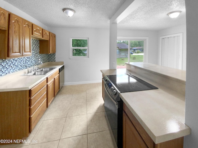 kitchen featuring dishwasher, sink, light tile patterned floors, range with electric cooktop, and decorative backsplash