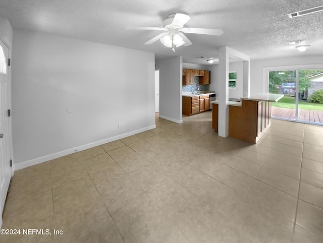 kitchen with ceiling fan, a textured ceiling, tasteful backsplash, and a breakfast bar