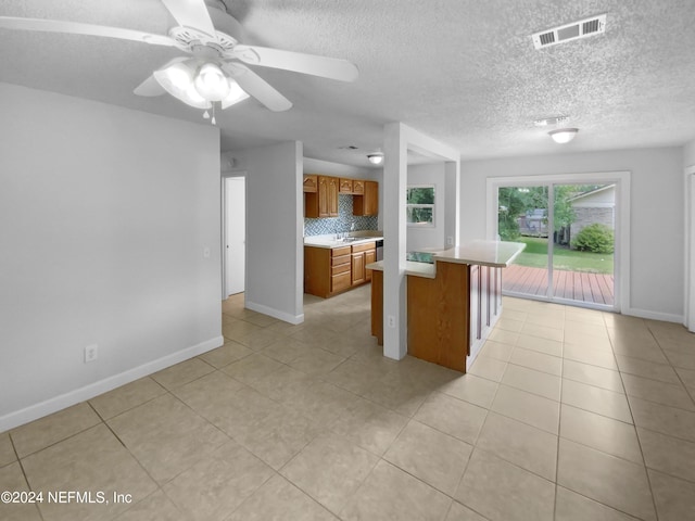 kitchen with ceiling fan, a textured ceiling, tasteful backsplash, and light tile patterned flooring