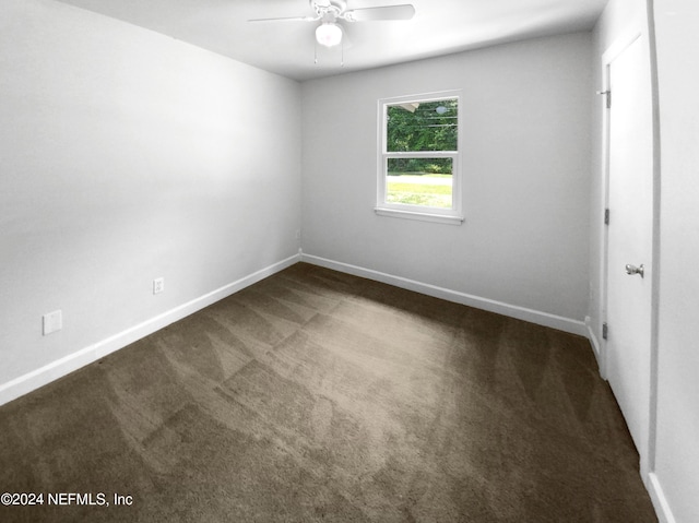 spare room featuring ceiling fan and dark carpet