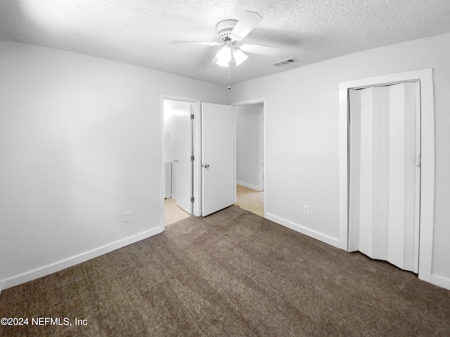 unfurnished bedroom featuring ceiling fan, a textured ceiling, a closet, and light carpet