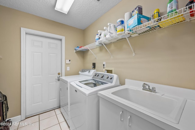 clothes washing area featuring sink, cabinets, separate washer and dryer, a textured ceiling, and light tile patterned floors