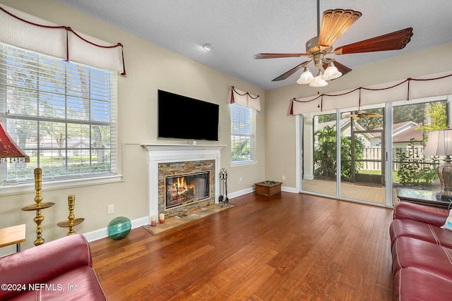 living room with ceiling fan, a fireplace, a textured ceiling, and hardwood / wood-style flooring