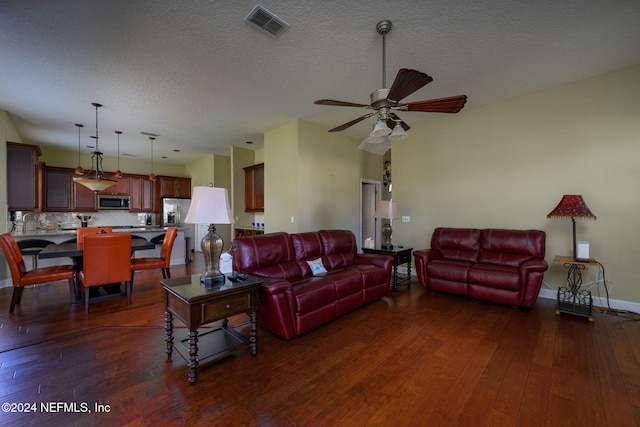 living room with a textured ceiling, dark hardwood / wood-style flooring, and ceiling fan