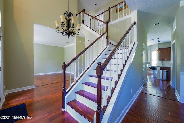 stairs featuring a textured ceiling, hardwood / wood-style flooring, and an inviting chandelier