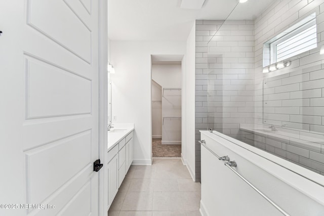 full bath with baseboards, tile patterned floors, a spacious closet, walk in shower, and vanity