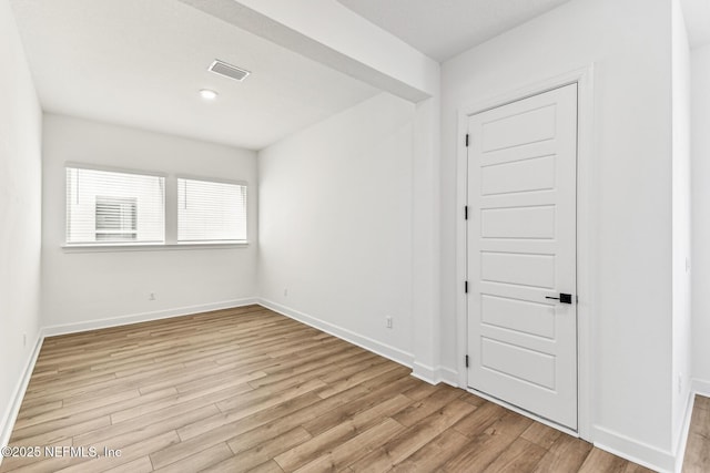 spare room with baseboards, visible vents, and light wood finished floors