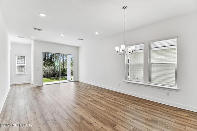 interior space featuring baseboards, visible vents, a chandelier, and wood finished floors