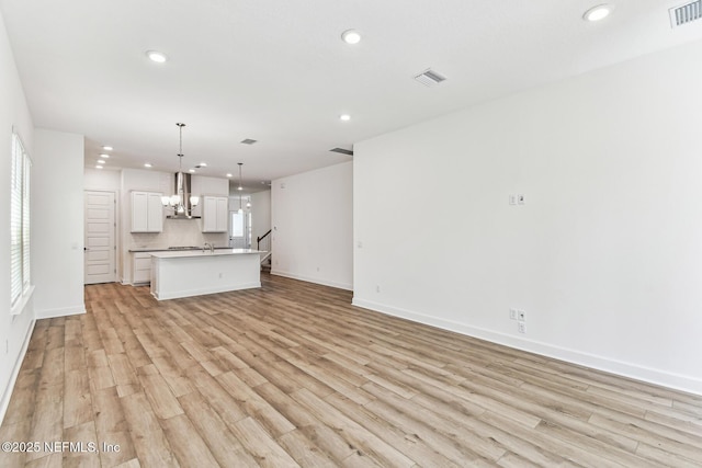 unfurnished living room with a notable chandelier, recessed lighting, visible vents, and light wood-style floors