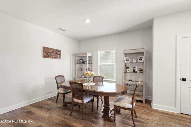 dining area with a textured ceiling and dark wood-type flooring