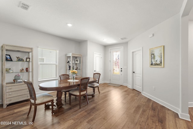 dining space featuring a textured ceiling, a healthy amount of sunlight, and dark wood-type flooring